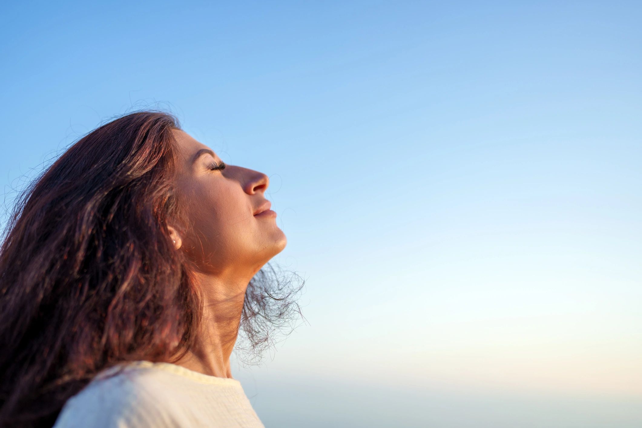 Woman breathing fresh air under blue sky