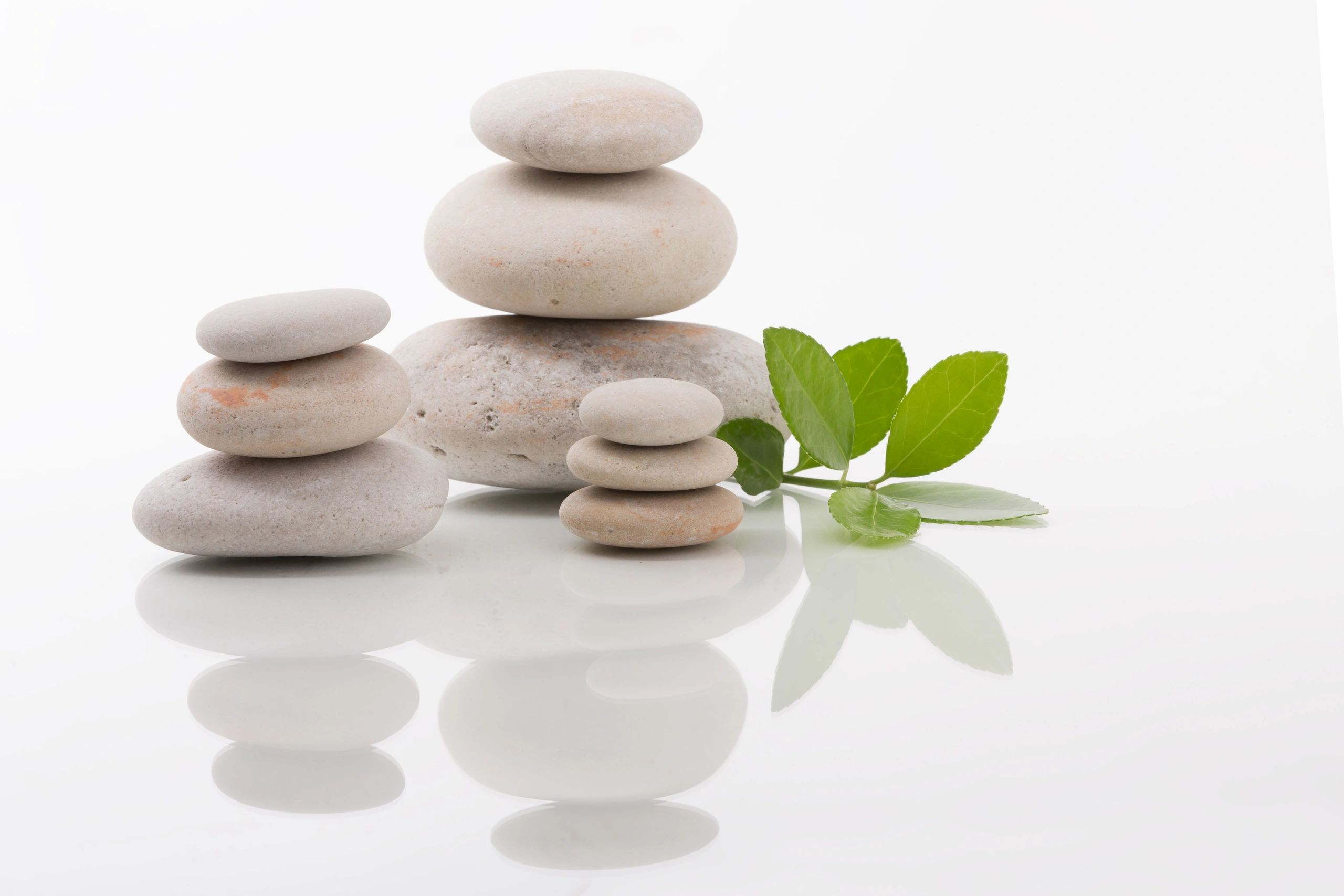 Balanced stones with green leaves representing calm and emotional balance