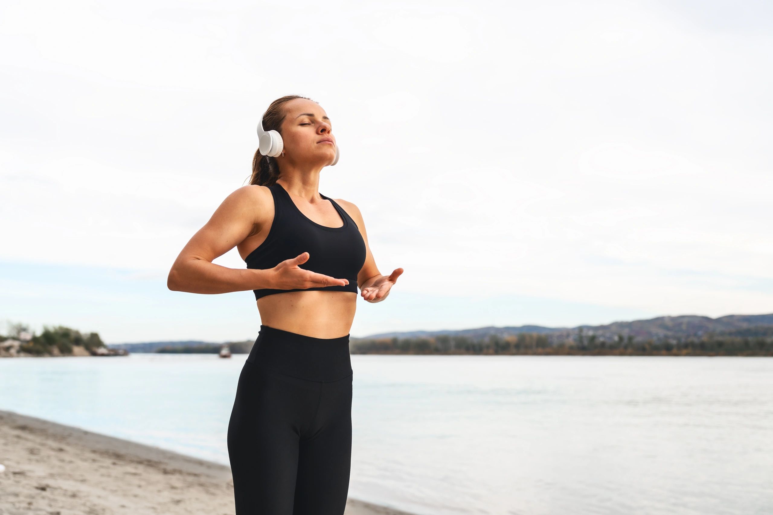 Woman practicing breathing exercise outdoors by river