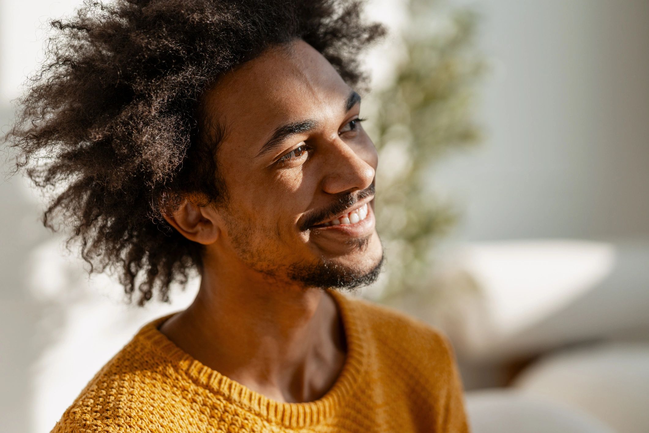 Young adult Black man smiling in warm sunlight at home