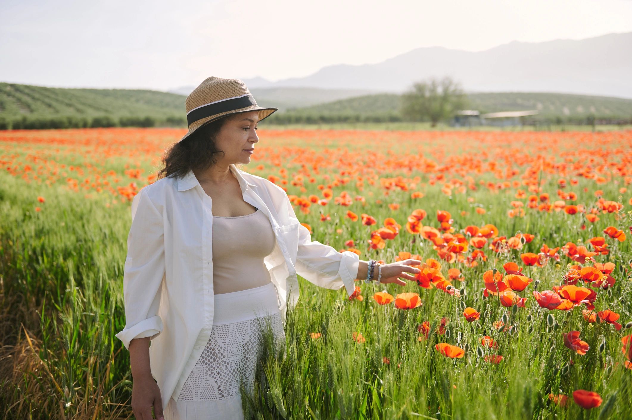 Woman walking through a vibrant poppy field at sunset
